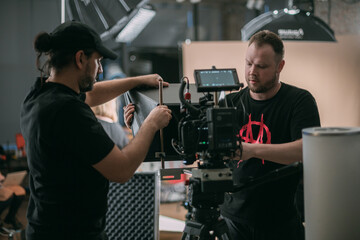 Canvas Print - Director of photography with a camera in his hands on the set. Professional videographer at work on filming a movie, commercial or TV series. Filming process indoors, studio