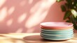 © Kin no Hikari - A stack of colorful plates against a soft pink background, featuring serene lighting and shadows that create a warm ambiance.