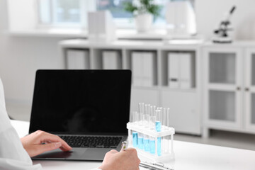 Wall Mural - Doctor with laptop at table in clinic, closeup view