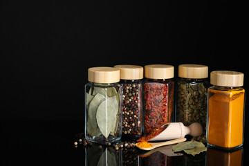 Poster - Different spices in glass jars on black mirror surface, space for text