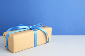 Poster - Gift box with blue satin bow on color background. Space for text