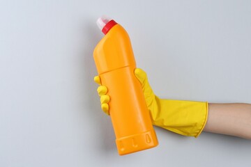 Wall Mural - Woman holding toilet cleaner in bottle on light background, closeup