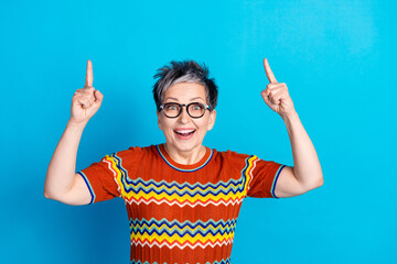 Poster - Photo of nice aged lady direct fingers up empty space wear t-shirt isolated on blue color background