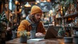 © Resi - Young freelancer working on laptop in cozy coffee shop