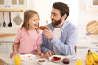 © New Africa - Father and his cute little daughter having breakfast at table in kitchen on sunny morning