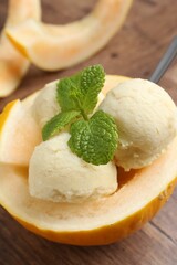 Canvas Print - Scoops of tasty melon sorbet with mint in fresh fruit on wooden table, closeup