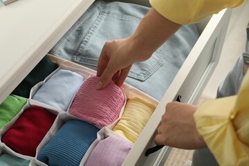 Woman organizing clothes in chest of drawers indoors, closeup