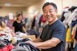 © Larisa - Happy man sorting clothing at charity event, engaging community