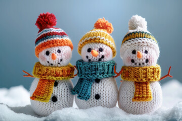 Three cheerful snowmen wearing colorful knitted hats and scarves, standing together in the snow, creating a festive and cozy winter scene.