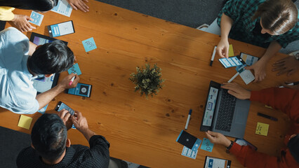 Programmer sharing Ux Ui design for mobile phone interface idea with software developer at meeting while designer writing idea at sticky notes. Start up team develop wireframe prototype. Convocation.