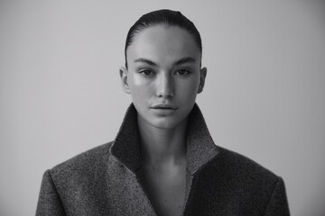 Confident Gaze: Minimalist fashion portrait of a young woman with a sharp, direct gaze, showcasing a sleek, modern look in a black and white aesthetic.  