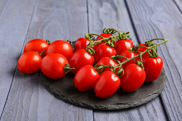 Board with fresh cherry tomatoes on blue wooden background