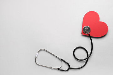 Sticker - Stethoscope and red heart on light background.  Cardiology concept