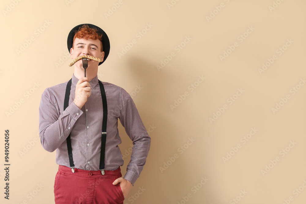 Young man in traditional German clothes with sausage on beige background