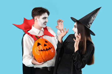 Wall Mural - Young couple dressed for Halloween with pumpkin on blue background