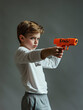 © sunaiart - The boy in the white shirt and grey shorts proudly held up his gun toy, which had the word 'BANG!' written on it, ready for his imaginative game of pretend battles.