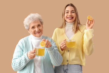 Poster - Young woman and her grandmother with glass cups of lemon tea on beige background