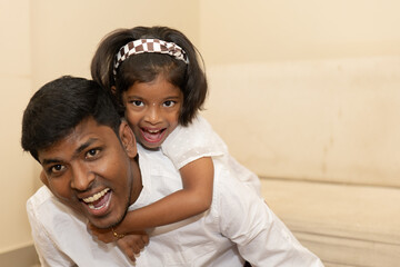 A joyful moment between a father and daughter at home, sharing laughter and playful affection in a cozy living room