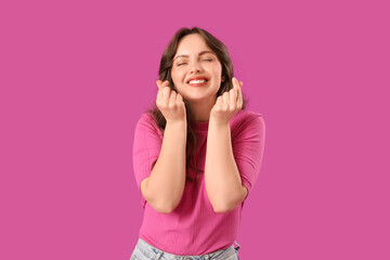 Poster - Happy young woman showing heart gesture on purple background. Valentine's Day celebration