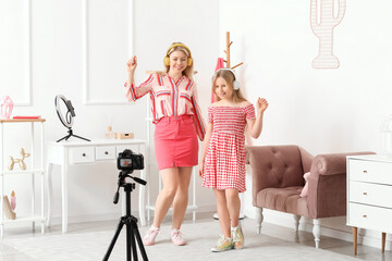 Poster - Beautiful female blogger with her daughter listening music and recording video at home