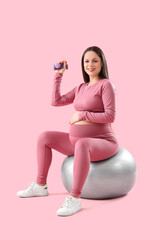 Sticker - Sporty pregnant woman with dumbbell training on fitball against pink background