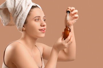 Wall Mural - Young woman in towel with serum on brown background, closeup