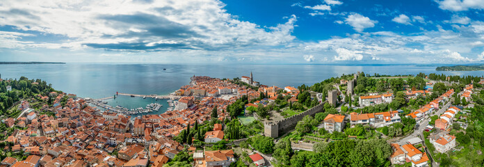 Aerial view of Piran medieval old town in Istria Slovenia with red rooftops, city wall, catholic church, popular tourist destination