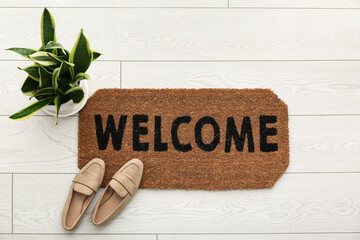 Wall Mural - Brown door mat, houseplant and shoes on white floor in hallway