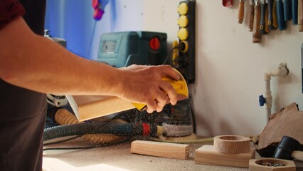 Sticker - Manufacturer working in joinery using sanding block to remove imperfections on wood piece. Woodworking specialist using coarse grade sandpaper to do manual sanding on lumber, camera B close up