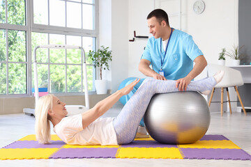 Sticker - Male physiotherapist and mature woman with fitball training in rehabilitation center