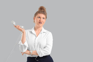 Wall Mural - Young beautiful businesswoman in formal clothes talking with phone on grey background