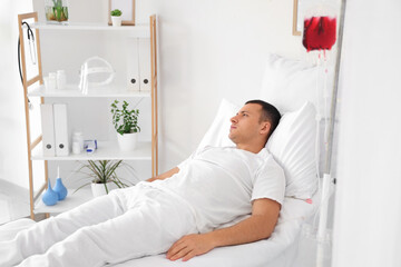 Canvas Print - Male patient transfusing blood on bed in hospital ward