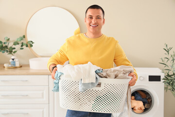 Sticker - Young man holding basket with dirty clothes in laundry room