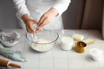 Wall Mural - Woman preparing traditional cinnamon rolls in kitchen