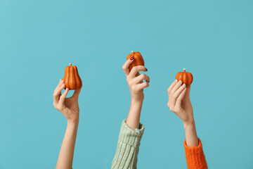 Many female hands with autumn candles in shape of pumpkins on blue background