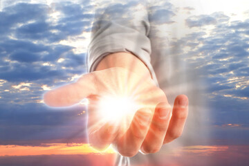 Man with holy light in hand against sky on sunrise, closeup