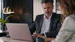 © JINGWEN - Professional businessman and woman collaborating on laptop at office desk discussing project and financial plan. Modern minimalistic interior with team of entrepreneurs working together.