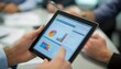 © irawan - Close-up of a Hand Holding a Tablet Showing Charts and Graphs