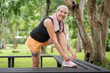 © Natee Meepian - Smiling senior Caucasian woman tying shoes on park bench