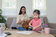 © Natee Meepian - Young girl organizing school supplies with her mother at home