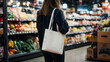 © Phichitpon - Consumption, eating and eco concept - woman with white reusable canvas bag for buying food through supermarket on background