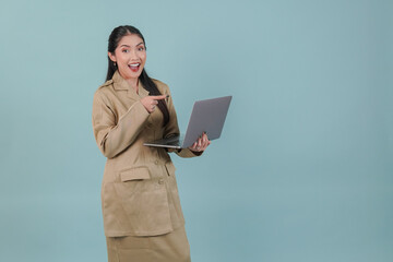 Wall Mural - Cheerful Indonesian government worker woman wearing khaki uniform pointing to the laptop she holds.