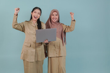 Wall Mural - Two joyful government worker woman holding laptop with a happy successful expression.