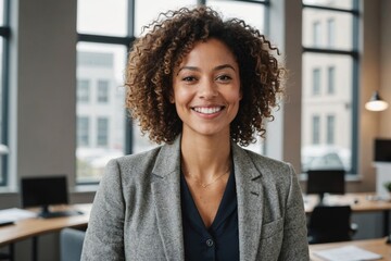 Portrait of happy biracial casual businesswoman with curly hair over model of building in office. business, work and architecture, unaltered.