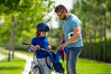 Canvas Print - Father helping son get ready for school. Happy fathers day. Father teaching son cycling on bike. Father learn little son to ride a bicycle. Father support and helping son. Fathers day concept.