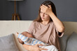 © sementsova321 - Caucasian tired exhausted woman gently rocking her newborn baby while sitting in couch in the nursery being sleepy suffering headache having sad look feeling fatigue