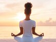 © DuangphonKPR - A young woman practicing yoga on the beach at sunrise, with a calm ocean backdrop