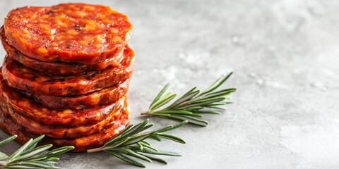 Wall Mural - Chorizo slices stacked on top of each other next to a sprig of rosemary