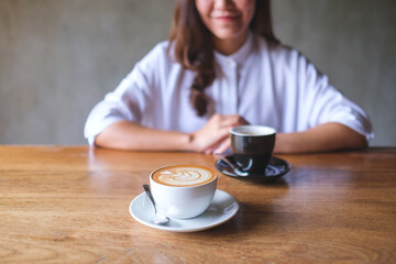 Canvas Print - Closeup image of a young woman with two cups of coffee on wooden table