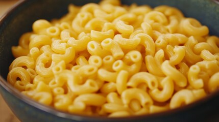 Wall Mural - A close-up shot of cooked macaroni pasta in a blue bowl. The pasta is yellow and the bowl is in focus. The image is perfect for representing simplicity, comfort food, or a basic ingredient.